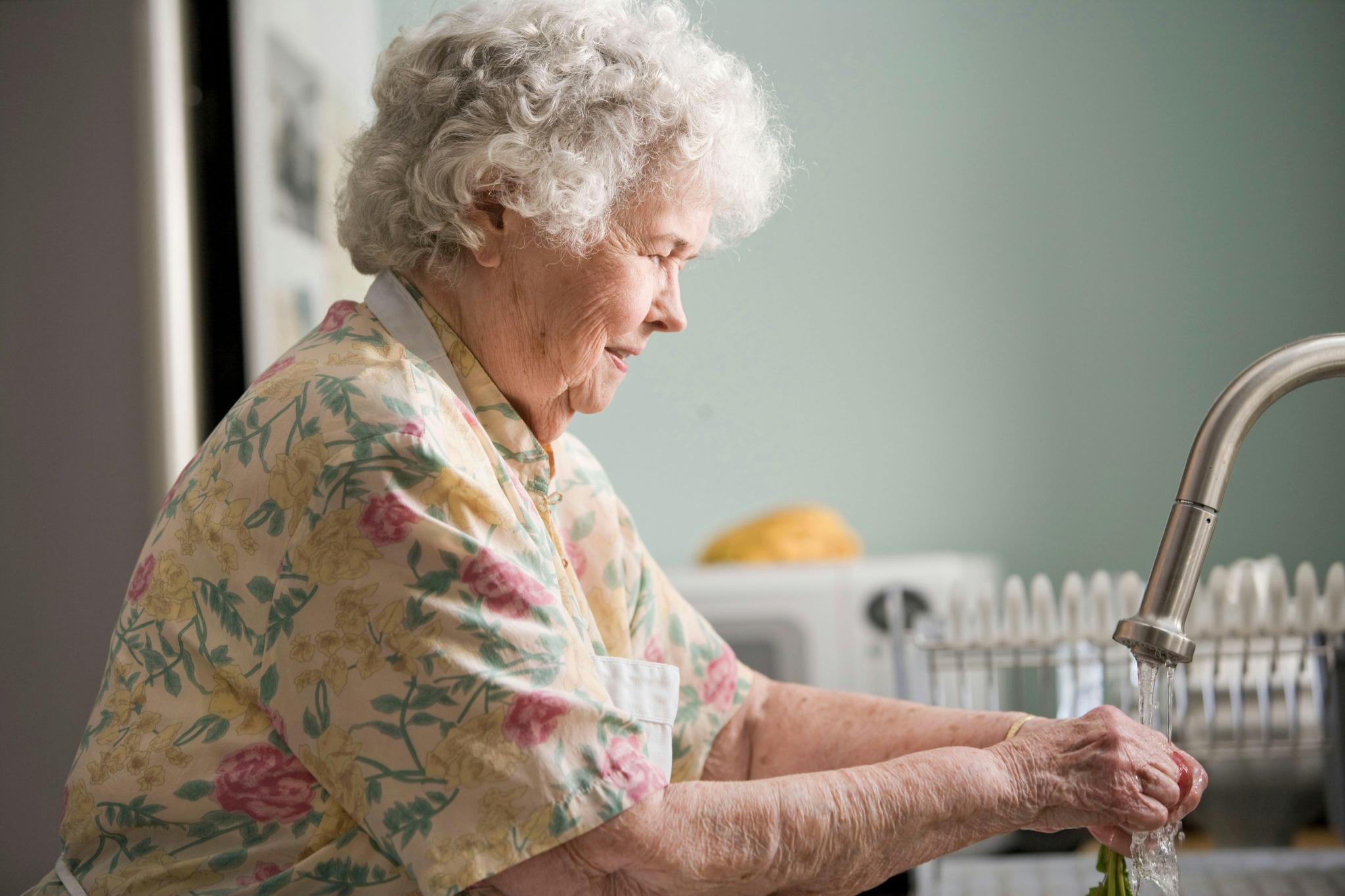 Senior woman washing vegetables in a kitchen