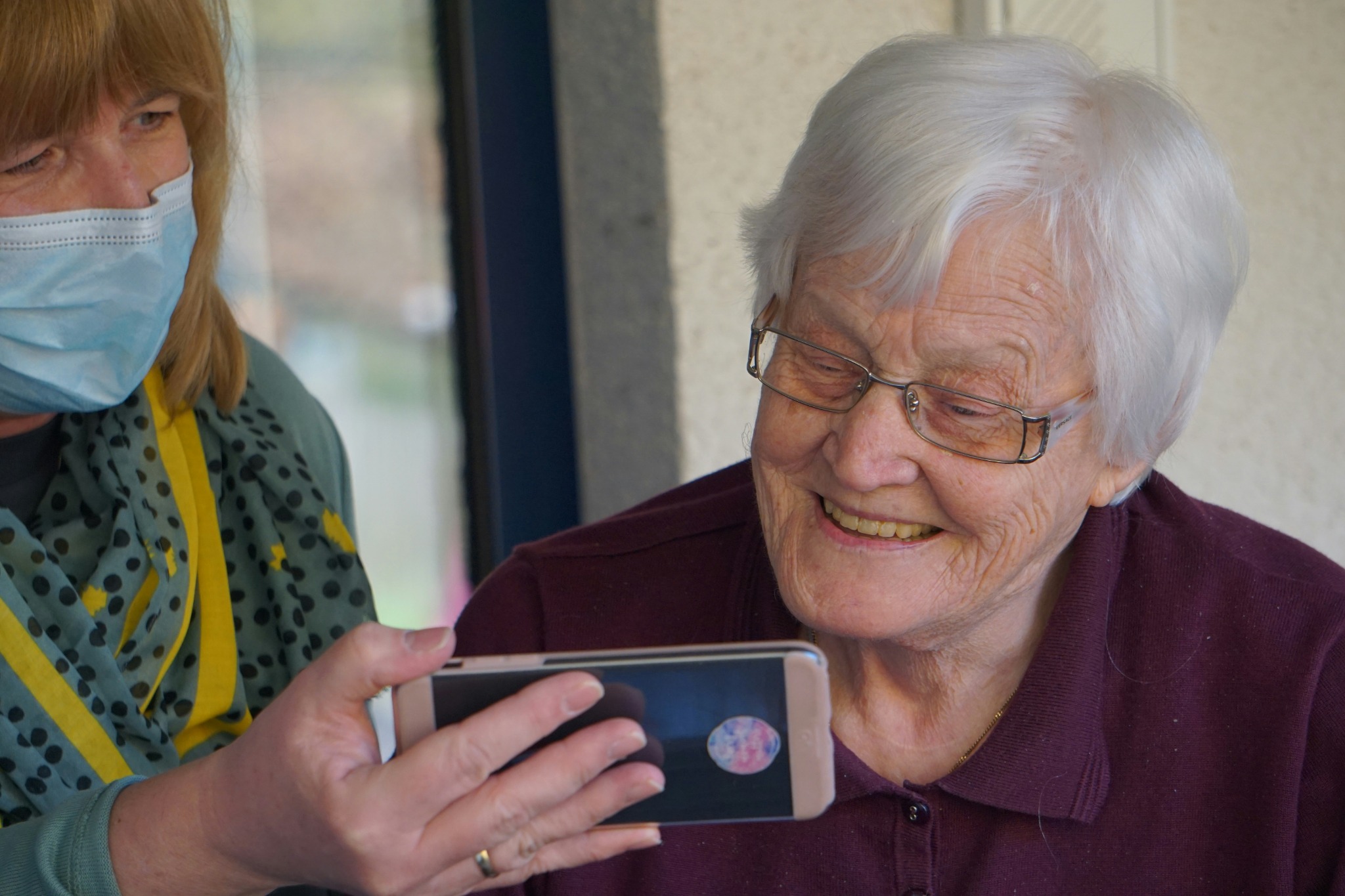 Older adult and care worker looking at a phone